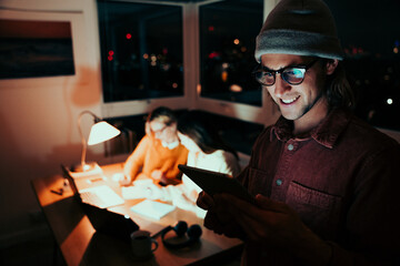 Caucasian male freelancer scrolling on digital tablet smiling receiving emails working late at night