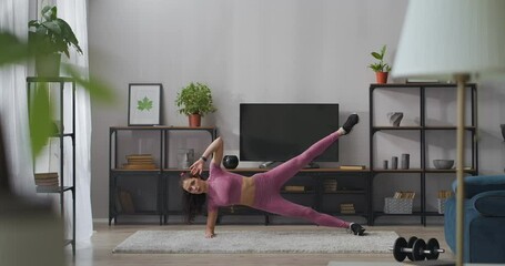 sporty lady is doing exercises for legs muscles in living room, home training for keeping fit and good feeling