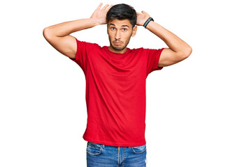 Young handsome man wearing casual red tshirt doing bunny ears gesture with hands palms looking cynical and skeptical. easter rabbit concept.