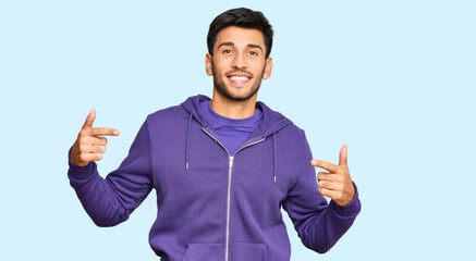 Fototapeta premium Young handsome man wearing casual sweatshirt looking confident with smile on face, pointing oneself with fingers proud and happy.