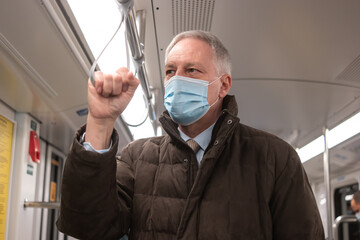Coronavirus covid travel concept, masked man commuter in a subway train