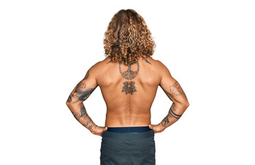 Handsome man with beard and long hair standing shirtless showing tattoos standing backwards looking away with arms on body