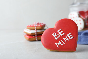 Obraz na płótnie Canvas Delicious heart shaped cookie with phrase Be Mine on light table, space for text. Valentine's Day