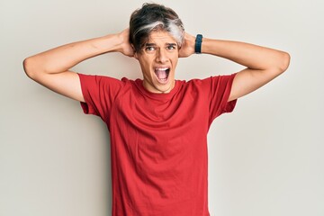 Young hispanic man wearing casual clothes crazy and scared with hands on head, afraid and surprised of shock with open mouth