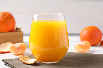 Glass of fresh tangerine juice on table