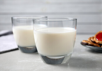 Glasses of delicious milk on light table