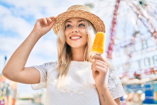 Young caucasian tourist girl smiling happy and eating ice cream at fairground.