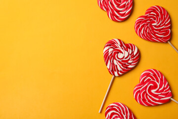 Fototapeta na wymiar Sweet heart shaped lollipops on orange background, flat lay with space for text. Valentine's day celebration