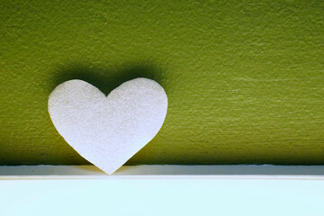 White heart on light box with green wall background.