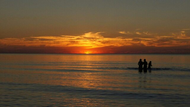 Silhouette People In Sea Against Sky During Sunset © robert höhna/EyeEm