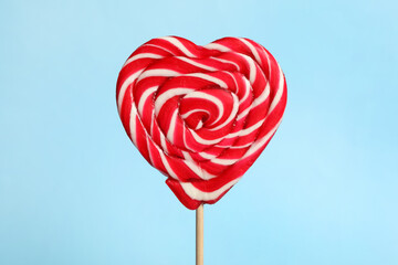 Sweet heart shaped lollipop on light blue background, closeup. Valentine's day celebration