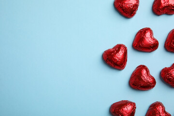 Heart shaped chocolate candies on light blue background, flat lay with space for text. Valentine's day treat