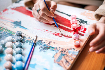 Painting for beginners, a woman draws a picture by numbers with acrylic paints on canvas,painting a picture with a brush, a girl draws a picture, self-isolation, home hobby, creativity at home