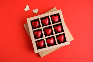 Tasty heart shaped chocolate candies on red background, flat lay. Happy Valentine's day