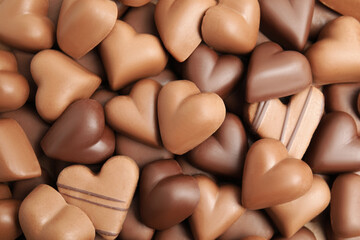 Tasty heart shaped chocolate candies as background, top view. Valentine's day celebration