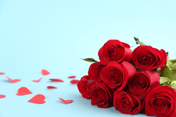 Beautiful red roses and paper hearts on light blue background, space for text. St. Valentine's day celebration