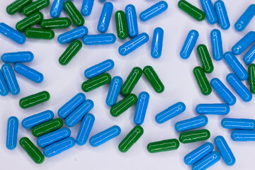 Green and blu capsules on white background. The concept of modern treatment, pharmacy, healthcare. 