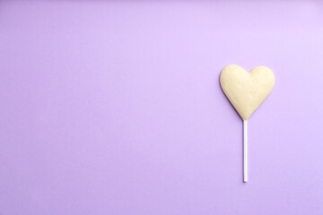 Chocolate heart shaped lollipop on light lilac background, top view. Space for text
