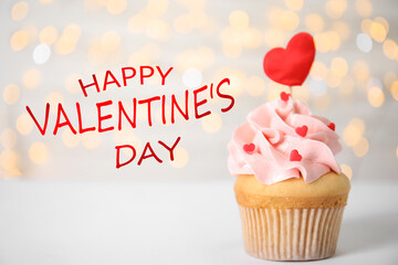 Happy Valentine's Day. Tasty cupcake on white table against blurred lights