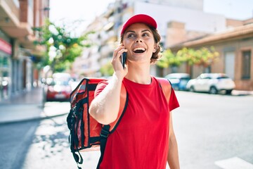 Delivery business worker woman wearing uniform and delivery bag smiling happy speaking on the phone