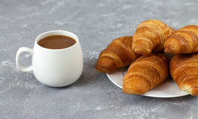Freshly baked croissants and cup of coffee on rustic stone table