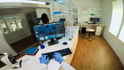 POV of team working to develop a new vaccine in modern equipped laboratory, man typing at computer. Group of biochemistry scientists examining virus evolution using high tech for researching treatment