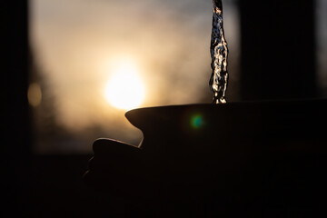 water pouring into clay pot in silhouette