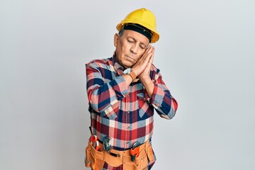 Senior hispanic man wearing handyman uniform sleeping tired dreaming and posing with hands together while smiling with closed eyes.