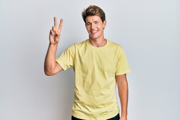 Handsome caucasian man wearing casual clothes showing and pointing up with fingers number two while smiling confident and happy.