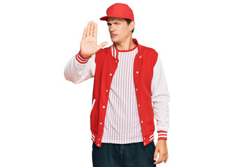 Handsome caucasian man wearing baseball uniform doing stop sing with palm of the hand. warning expression with negative and serious gesture on the face.