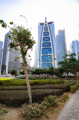 Obraz na płótnie Canvas Vue sur un quartier résidentiel et un parc urbain au centre de Dubaï. Verdure, banc, personnes au premier plan et hauts bâtiments à l'architecture moderne en arrière-plan.
