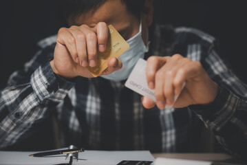 Credit card debt from Covid-19 concept, Asian men use the hand to hold the credit cards from bank debt and strain, unplanned spending, unemployment and economic losses.