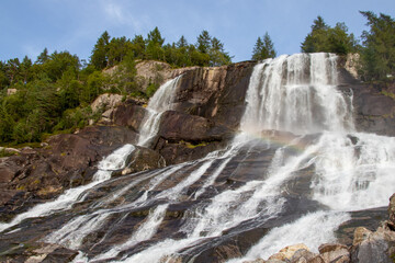 Fototapeta premium Beautiful Furebergsfossen waterfall in Norway, waterfall on rocky slope near road along the Hardangerfjord fiord