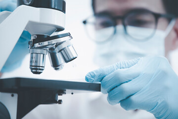 biochemical research scientist working with microscope for coronavirus, laboratory glassware...