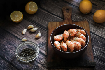Greenlandic shrimps. Boiled shrimp on a dark background with lemon and spices.Preparation of a dietary dish . Protein products. Source of omega 3 and omega 6 acids. Rustic style