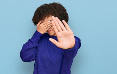 Young hispanic girl wearing casual winter sweater and glasses covering eyes with hands and doing stop gesture with sad and fear expression. embarrassed and negative concept.