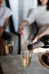 Champagne on the table is poured into a glass at a bachelorette party.