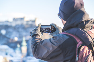 Making photos of Salzburg: Young tourist man is making photos of the old city of Salzburg, winter time