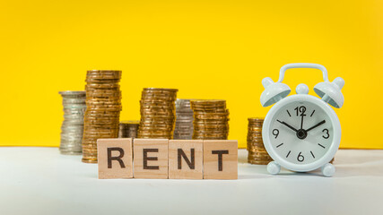 RENT wording on white table with house, coins and clock