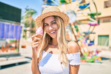 Young blonde tourist girl smiling happy eating ice cream at the fairground.
