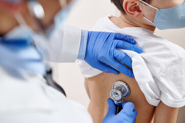 Close up of pediatrician using stethoscope, checking up heartbeat and lungs while auscultation in doctor office