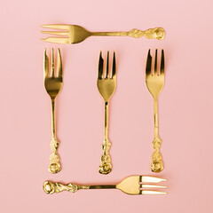 Minimal creative concept of gold forks making square symbol with nice pastel pink background. Celebration idea