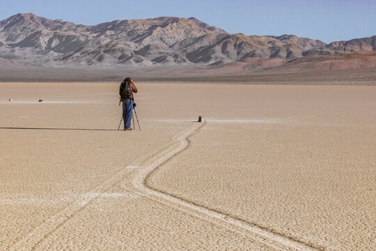 USA, Nevada, Death valley national park: the traveler photographs the famous moving rocks on the Racetrack playa. - Powered by Adobe