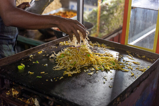 Sri Lankan man making kottu on the plate
