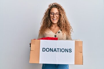 Beautiful caucasian teenager girl volunteer holding donations box winking looking at the camera...