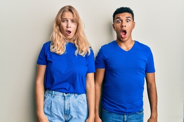 Young interracial couple wearing casual clothes afraid and shocked with surprise and amazed expression, fear and excited face.