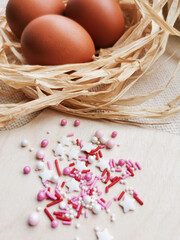 Obraz na płótnie Canvas Confectionery sprinkles. Chicken eggs in a nest made of straw. Easter. 