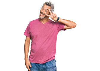 Middle age grey-haired man wearing casual clothes doing peace symbol with fingers over face, smiling cheerful showing victory