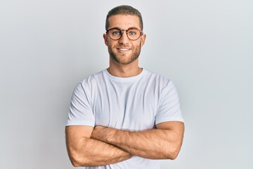 Fototapeta premium Young caucasian man wearing casual clothes and glasses happy face smiling with crossed arms looking at the camera. positive person.