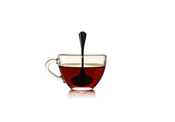 Transparent glass cup with tea and teaspoon. Isolated on a white background